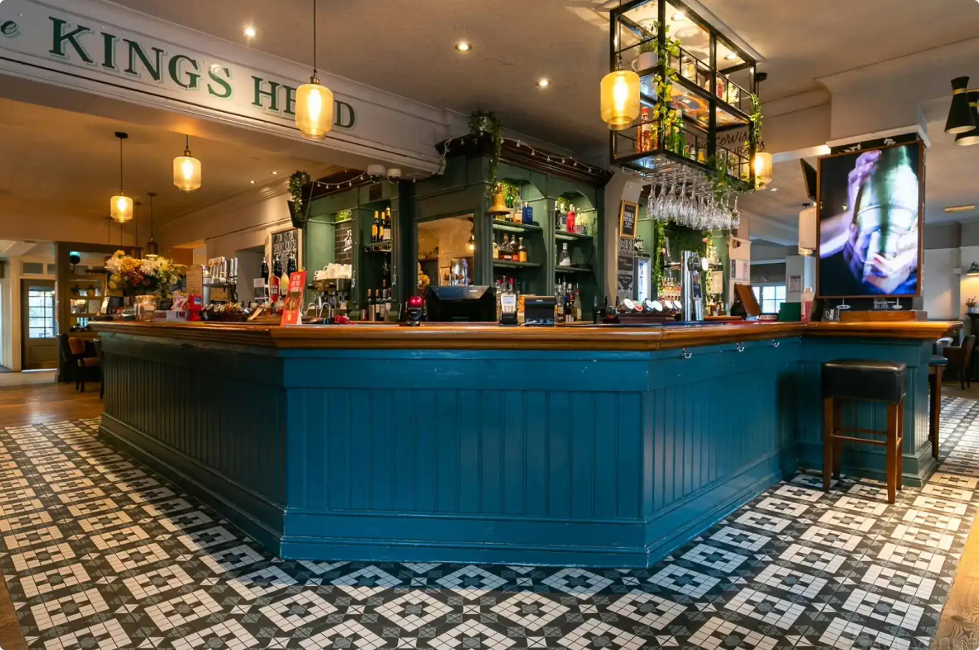 Inside the Kings Head: the painted Welcome to the Kings Head beam above the duck-egg blue bar